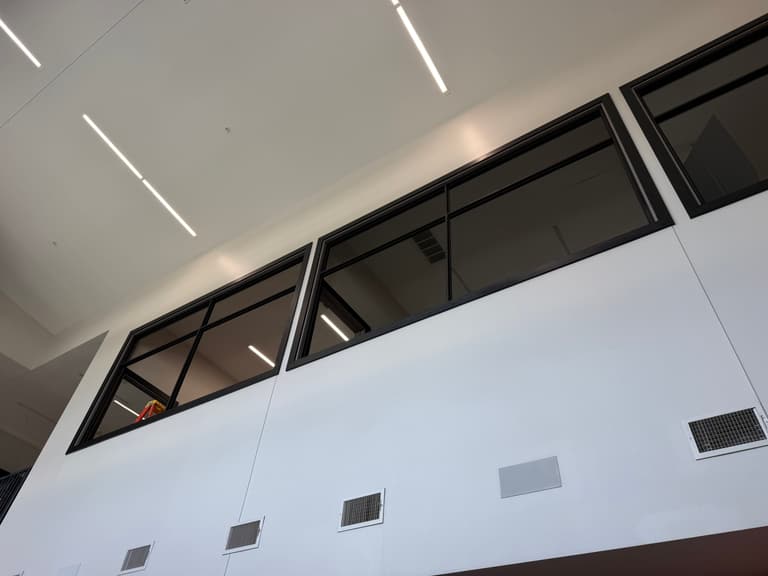 Black steel interior window frames set high along a white wall in a commercial building