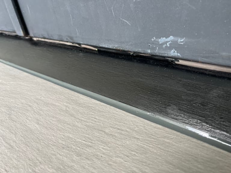The steel door frame after the repair: solid, smooth and painted black at the threshold