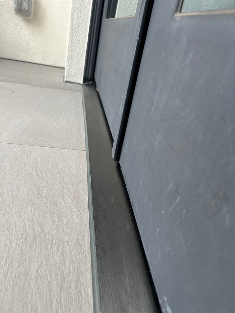 Standing view of the repaired steel door frame painted black down to the tile