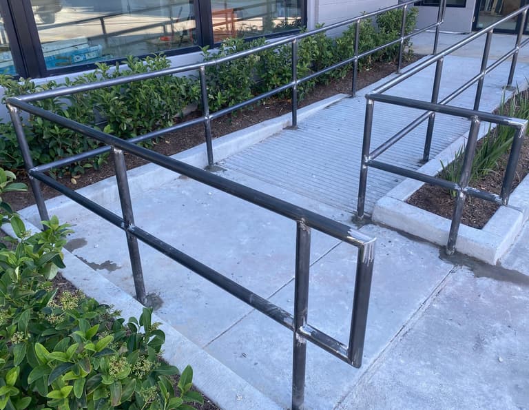 Steel pipe handrails with closed returns at the bottom of a concrete ramp (commercial job)