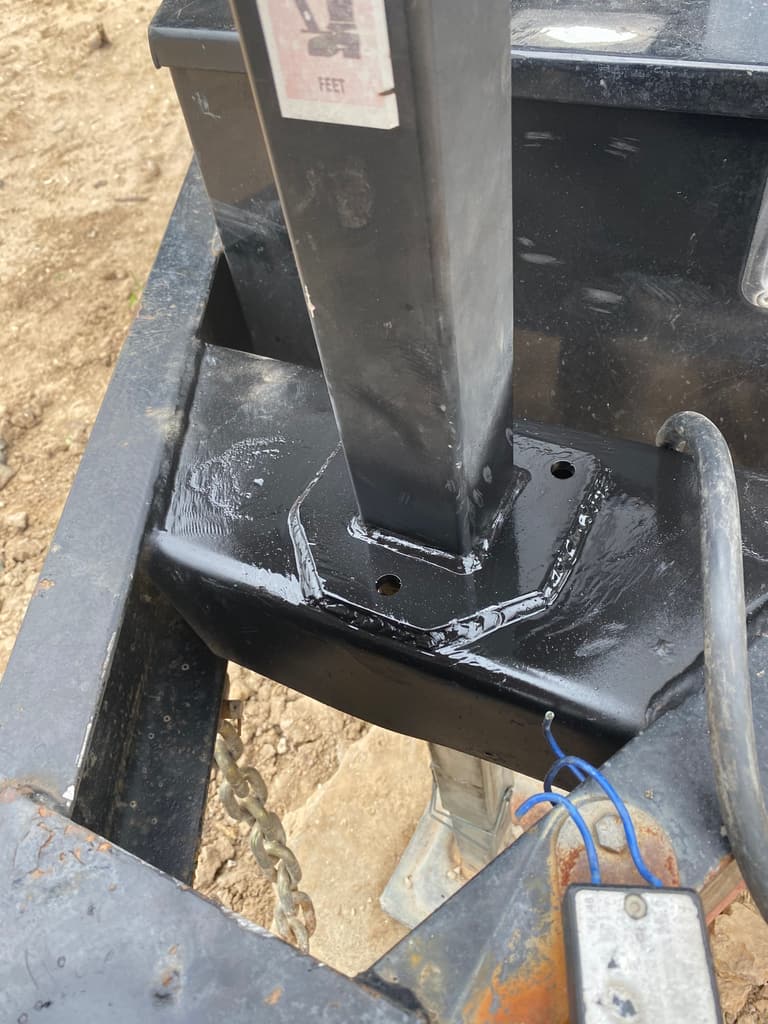 Repaired trailer jack mount painted black, the jack post standing square on its new plate